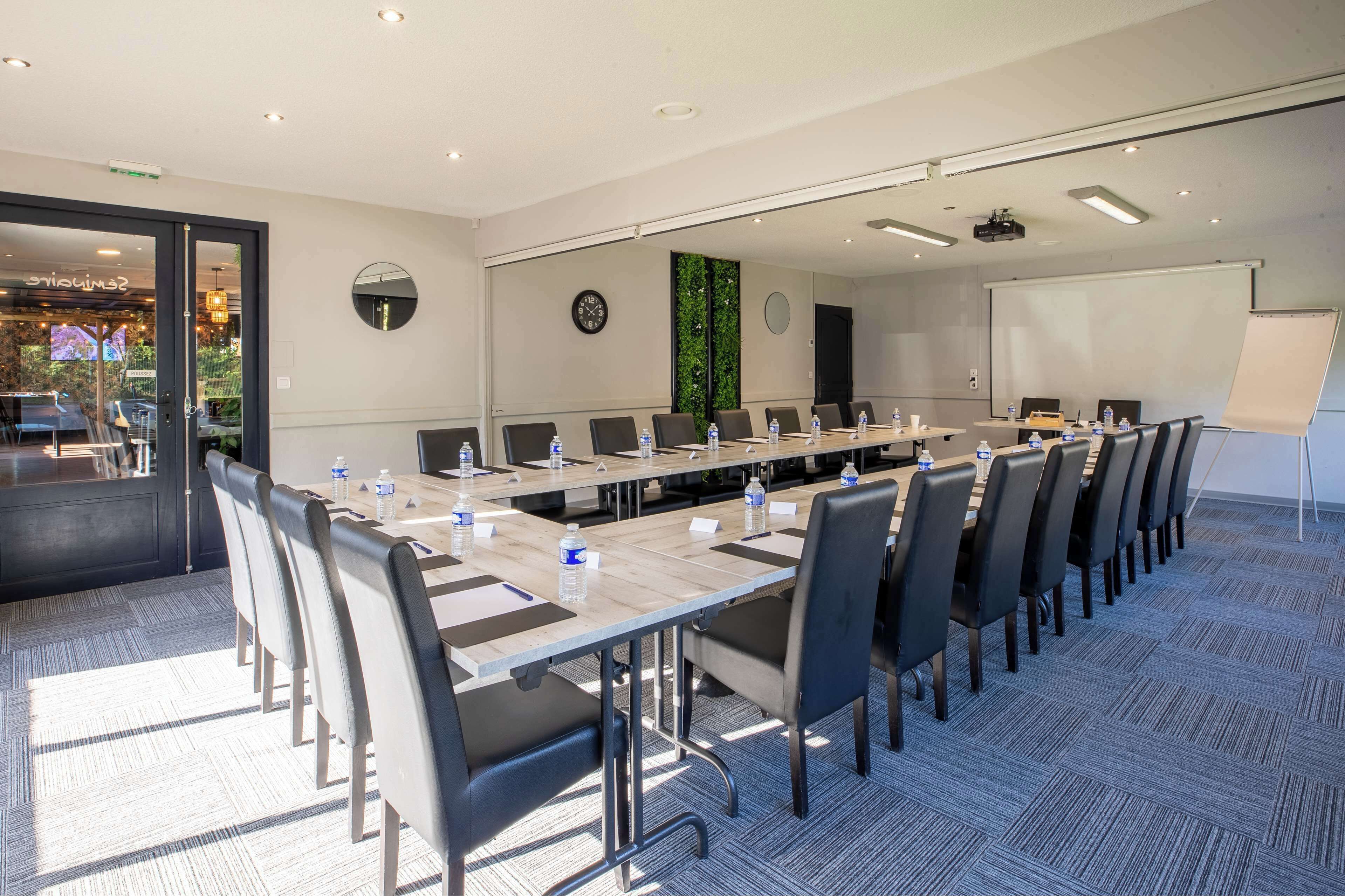 A conference room with a long table, chairs, a projector, and a whiteboard.
