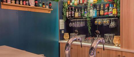 Una zona de bar con estantes llenos de botellas de licor, una barra y un grifo.