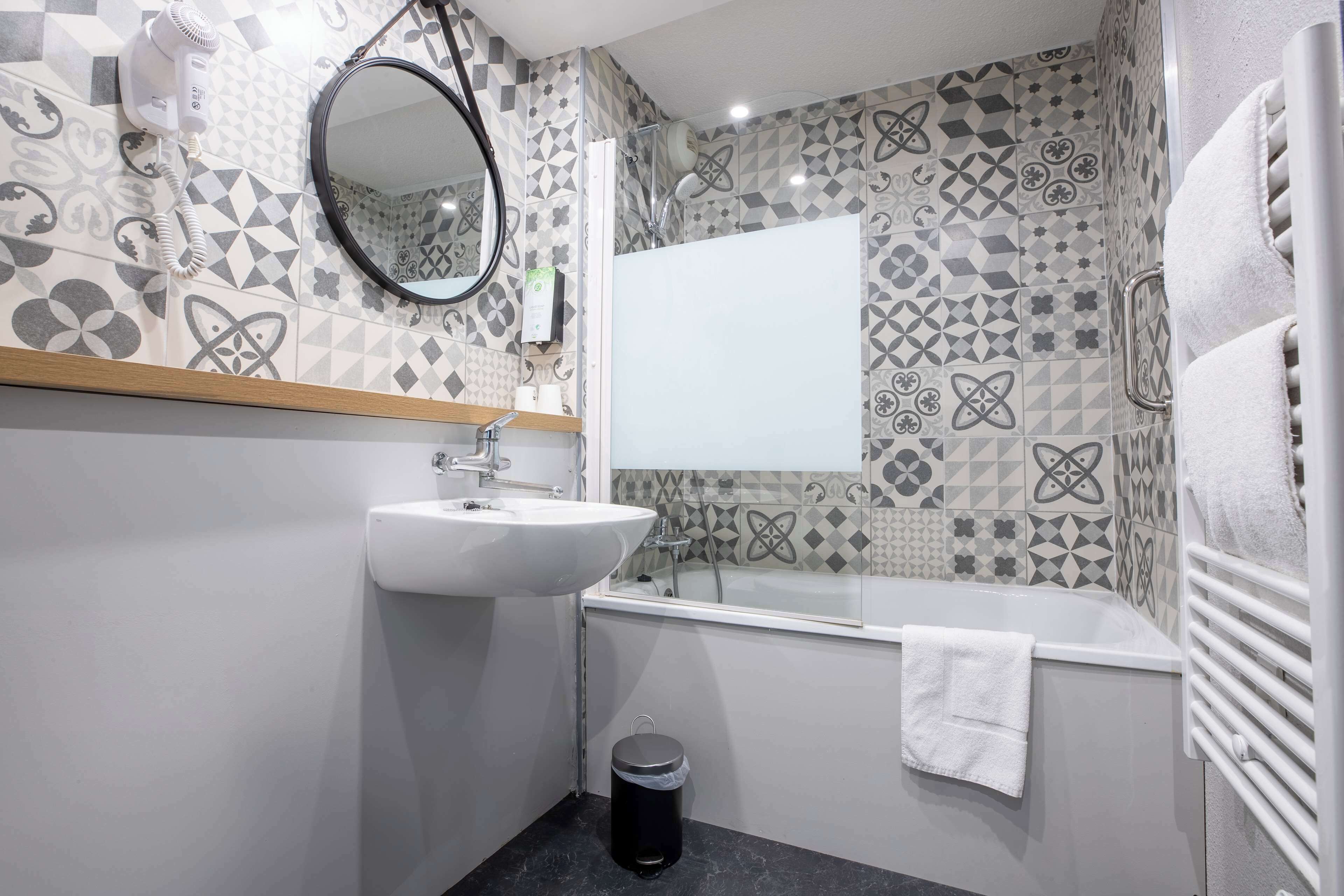 A bathroom with a sink, mirror, and shower.