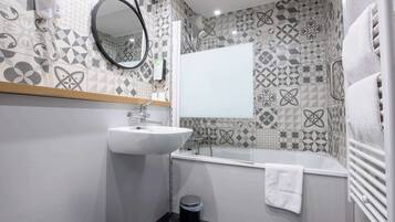 A bathroom with a sink, mirror, and shower.