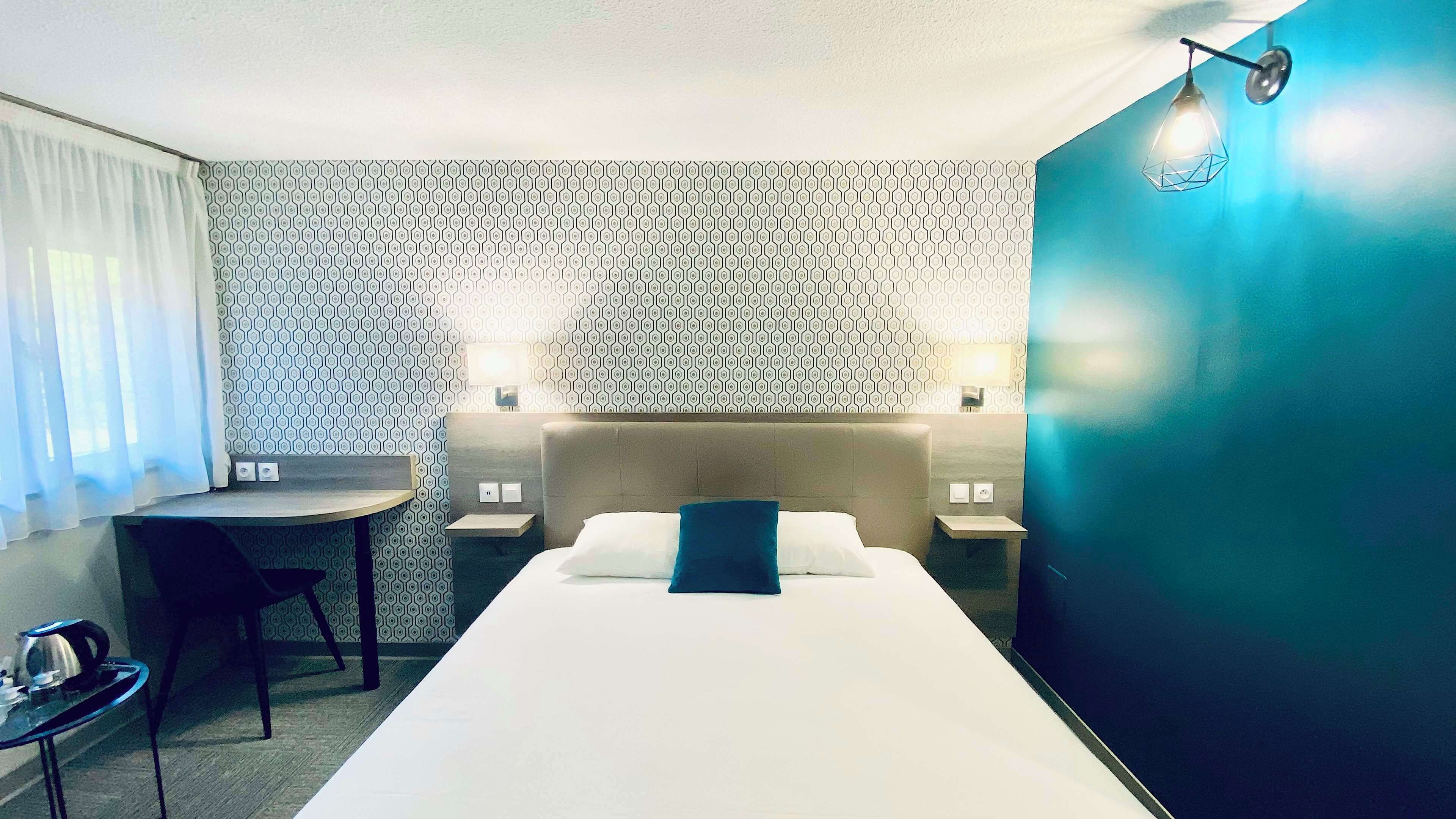 Une chambre d’hôtel comprenant un lit, un bureau, deux tables de chevet et une chaise.
