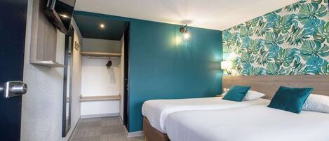 A hotel room with a bed, a wardrobe, a shower area, and a wall with a leaf pattern.