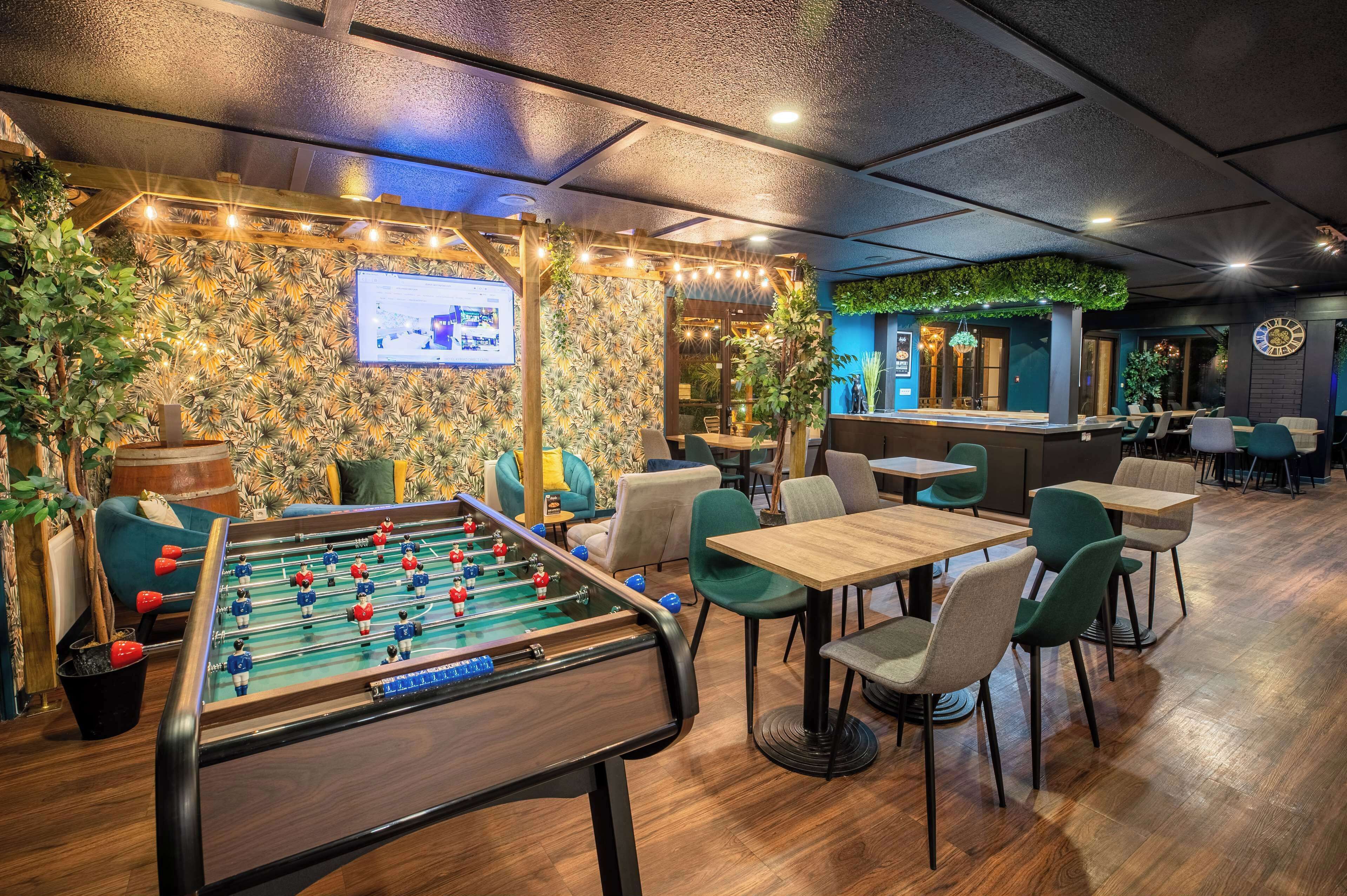 A cozy indoor space with a foosball table, comfortable seating, and a bar area.