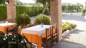 An outdoor patio with tables and chairs, stone pillars, and a gravel path. - Agriturismo Da Merlo (Mestre)