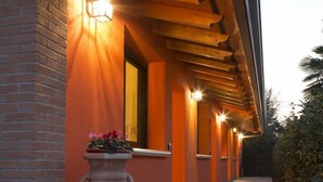 A corridor with a brick wall, a large decorative urn, and multiple illuminated wall sconces. - Agriturismo Da Merlo (Mestre)