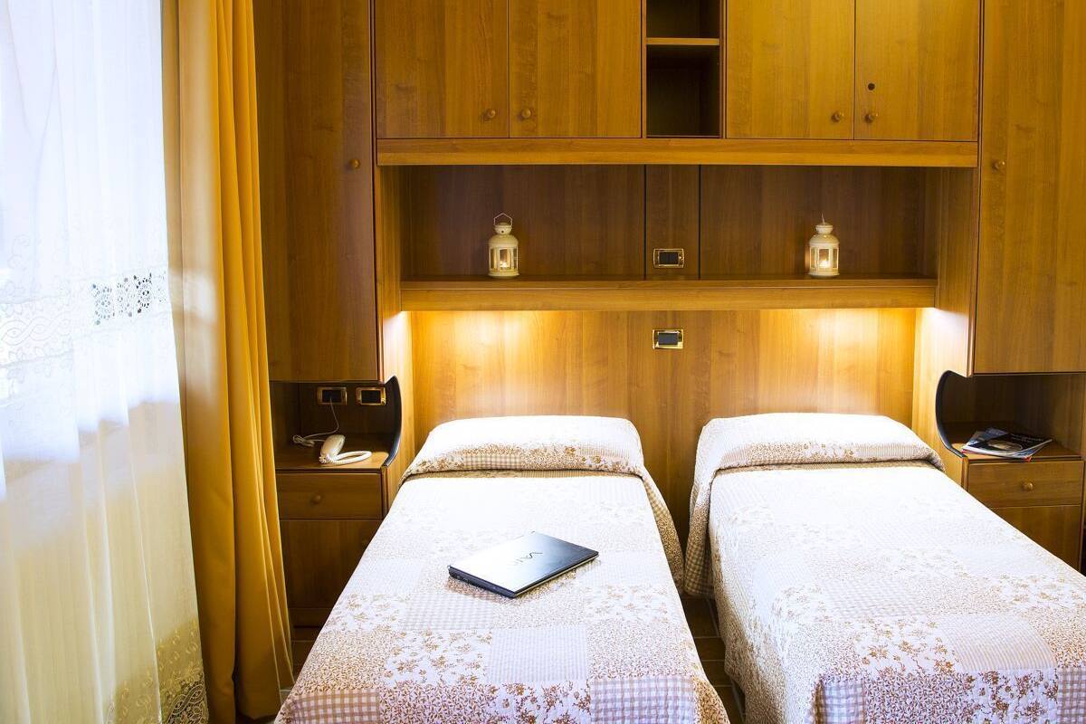 A hotel room with two beds, wooden cabinets, and bedside lamps.