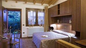 A bedroom with a bed, wooden furniture, a window with curtains, and a view of greenery outside. - Agriturismo Da Merlo (Mestre)