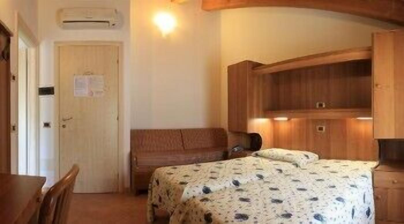 Una habitación pequeña con cama, un banco de madera, un escritorio y un armario.