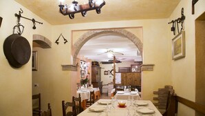 A dining area with a long table set for a meal, a chandelier, and a large pot hanging on the wall. - Agriturismo Da Merlo (Mestre)