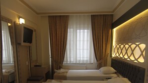 A hotel room with two beds, a TV, a mirror, and a window with curtains. - Hotel Grand Liza (Istanbul)