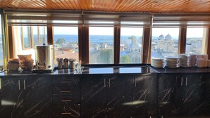 A kitchen with a marble countertop, wooden ceiling, and large windows with a city view. - Hotel Grand Liza (Istanbul)