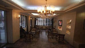 A hotel lobby with a chandelier, seating area, and a view through the windows. - Hotel Grand Liza (Istanbul)