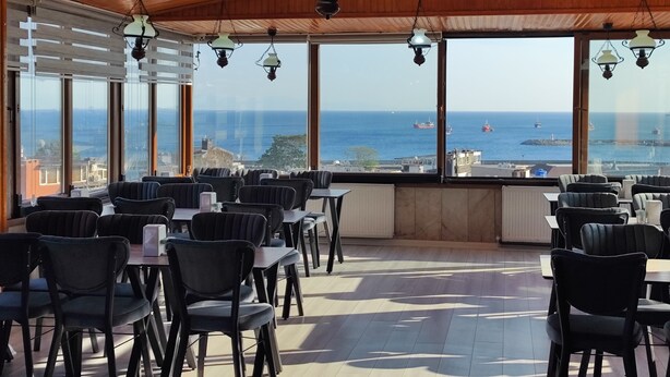 A restaurant with a view of the sea, featuring wooden ceiling and hanging lamps. - Hotel Grand Liza (Istanbul)
