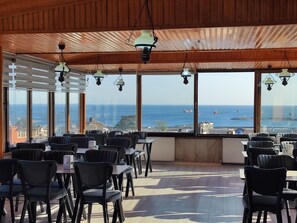 A restaurant with a view of the sea, featuring wooden ceiling and hanging lamps. - Hotel Grand Liza (Istanbul)