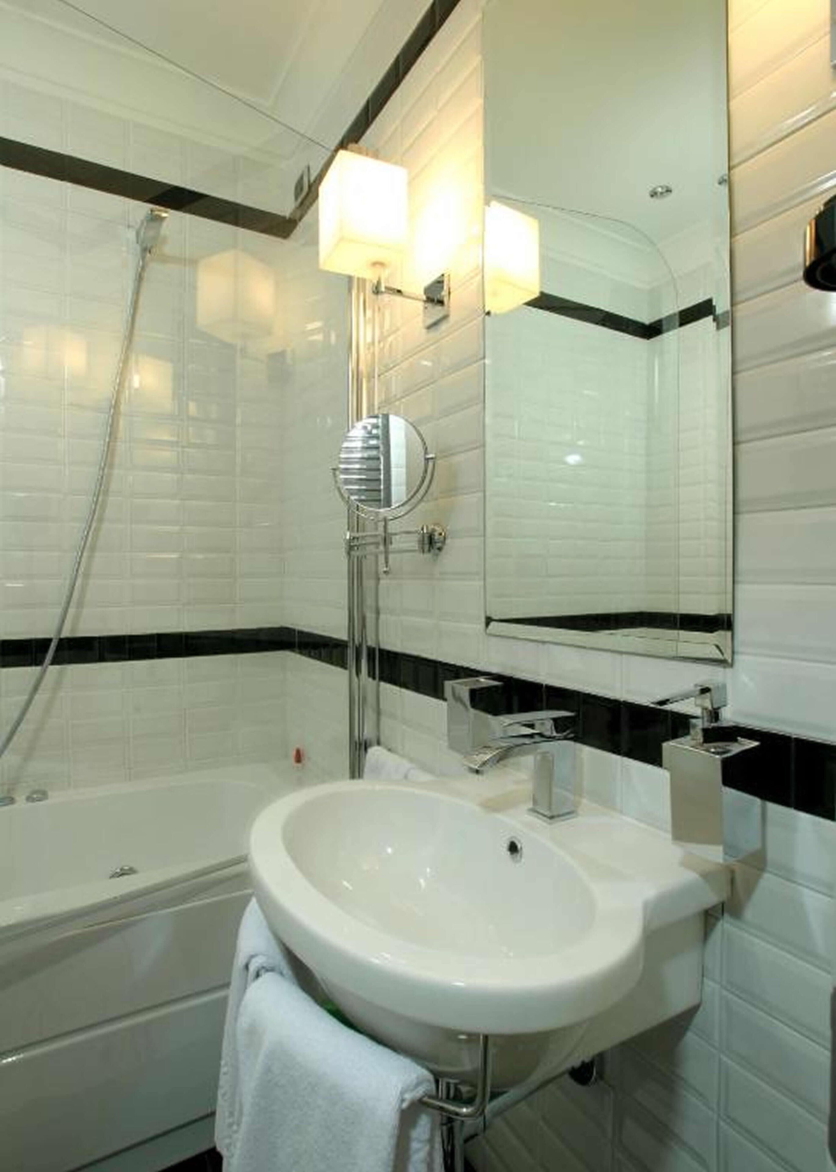 Une salle de bain moderne avec un lavabo blanc, un grand miroir et une baignoire.