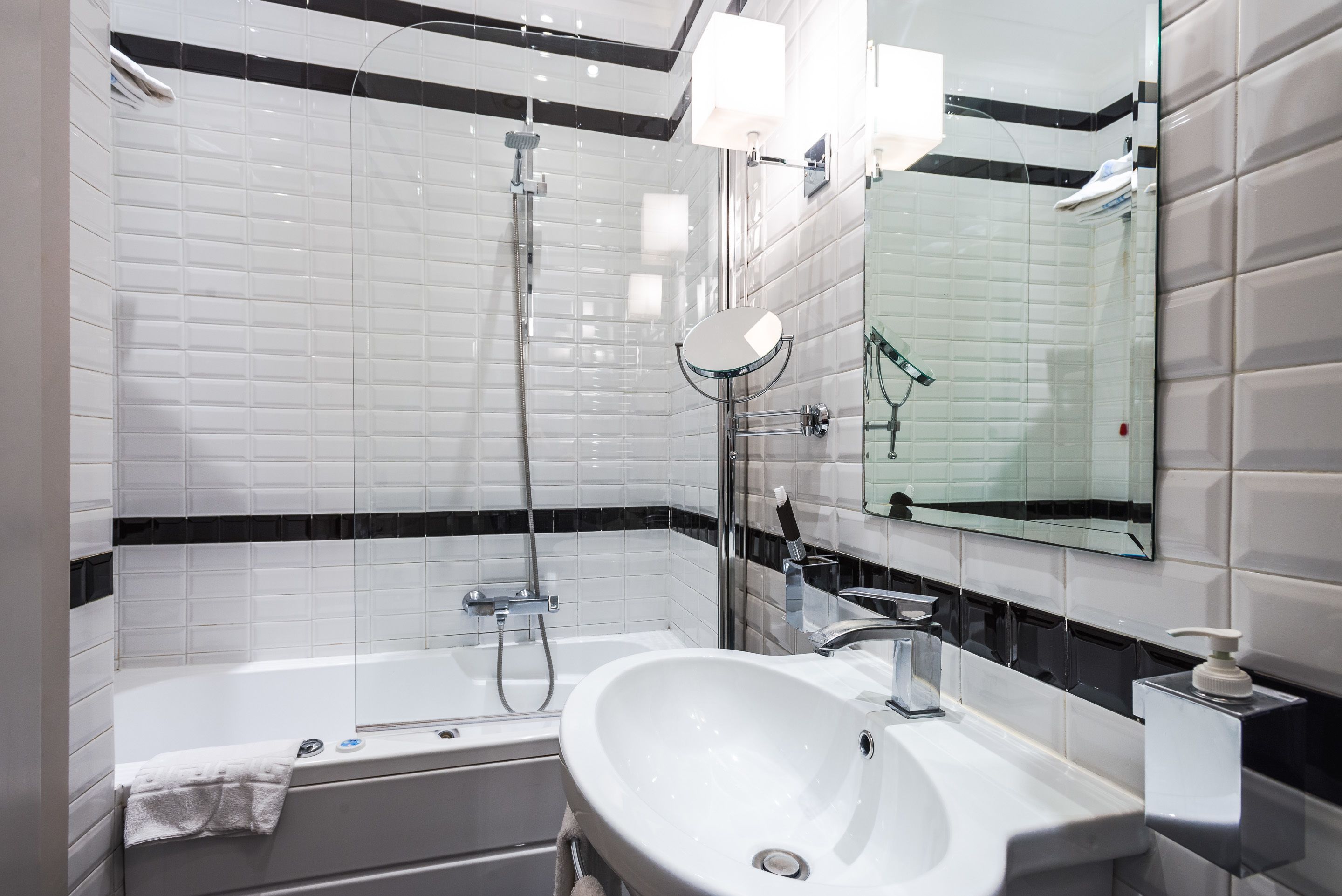 A modern bathroom with a white sink, a glass-enclosed shower, and a large mirror.