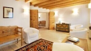 A spacious living room with wooden beams, a wooden bench, white sofas, a patterned rug, and a wooden cabinet. - Villa Toderini Agriturismo (Codogne)