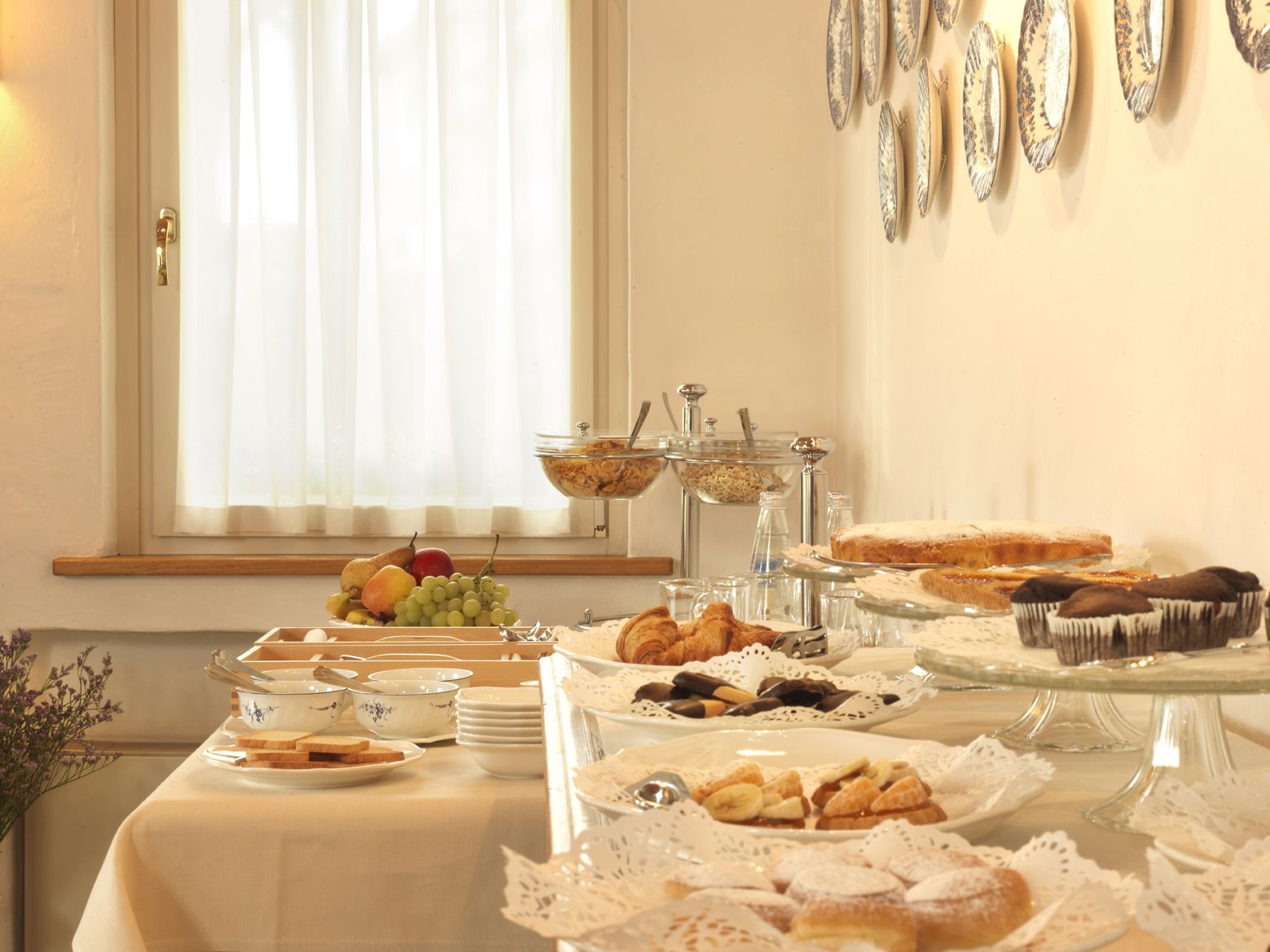 Ein Büfett mit verschiedenen Speisen, darunter Obst, Gebäck und Desserts, angerichtet auf Glasplatten.