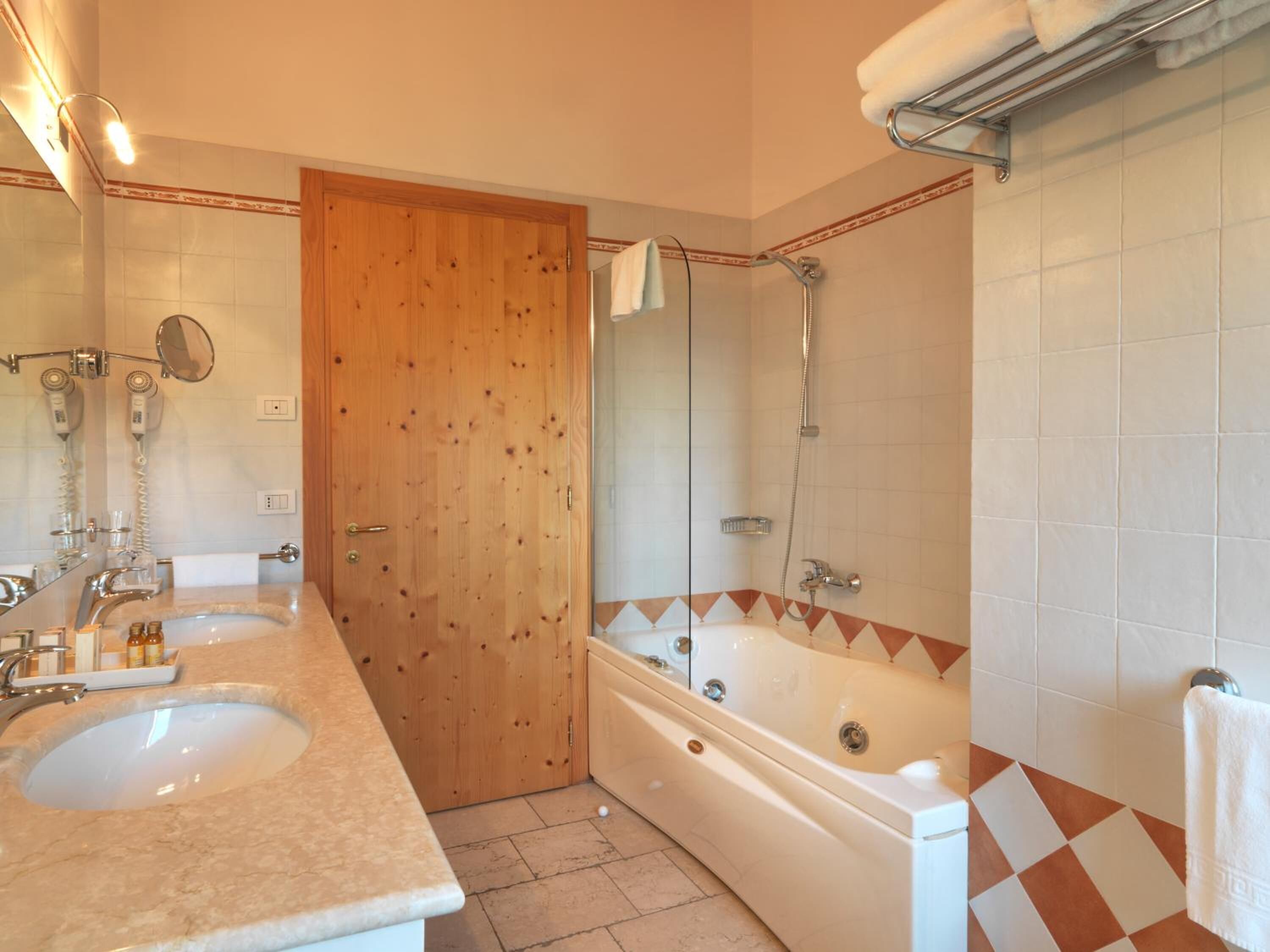 A bathroom with two sinks, a wooden door, a bathtub, and a shower.