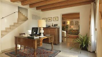 Un vaste espace de vie agrémenté d’un escalier en bois, d’une table à manger avec un tapis, et d’un coin cuisine avec une plante.