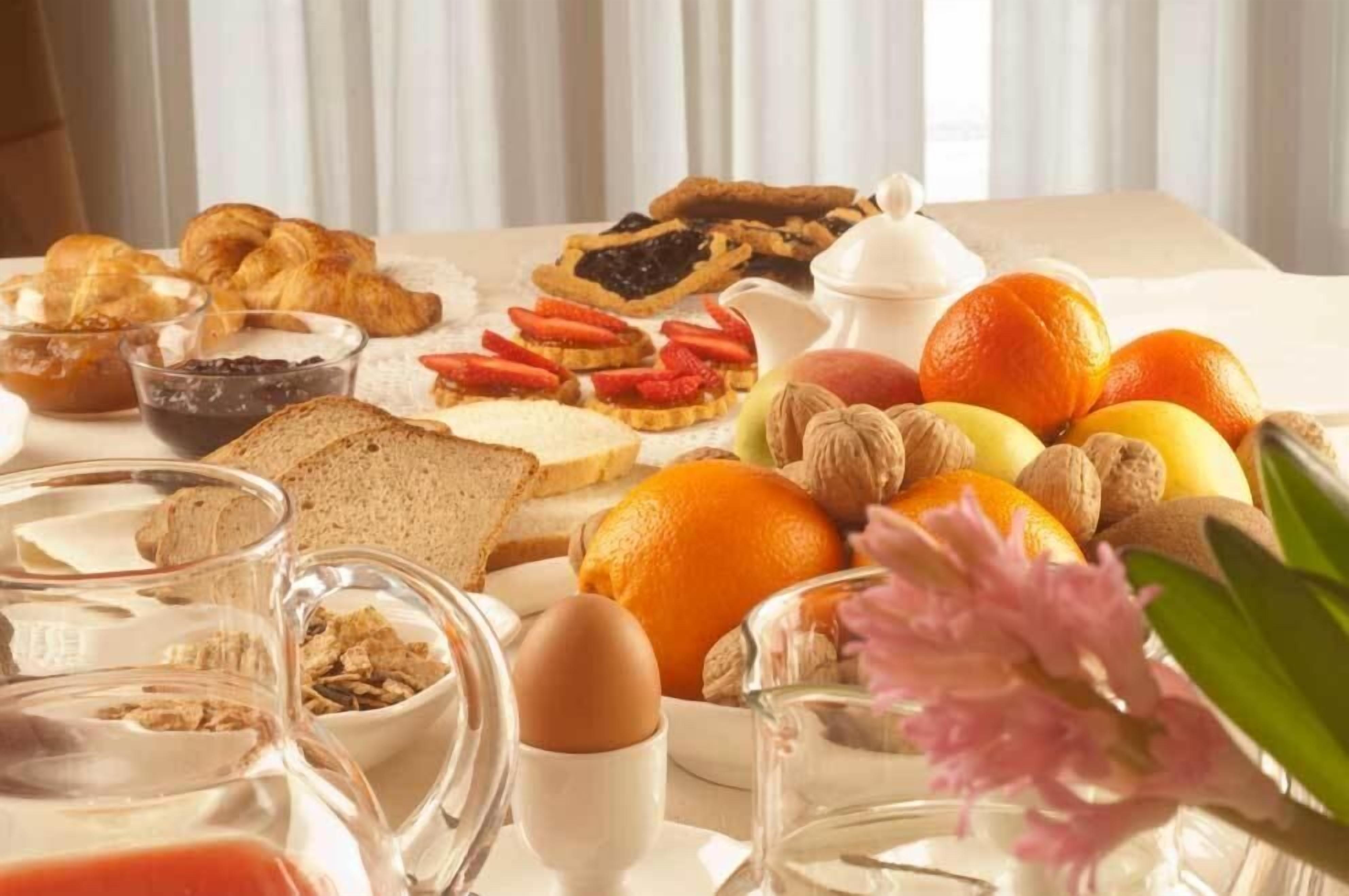 A breakfast spread with pastries, fruits, nuts, and beverages on a table.