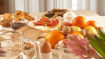 A breakfast spread with pastries, fruits, nuts, and beverages on a table.