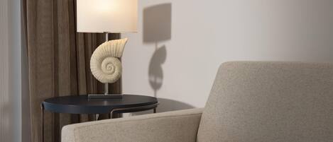 A modern room with a sofa, a round table with a lamp, and a curtain.