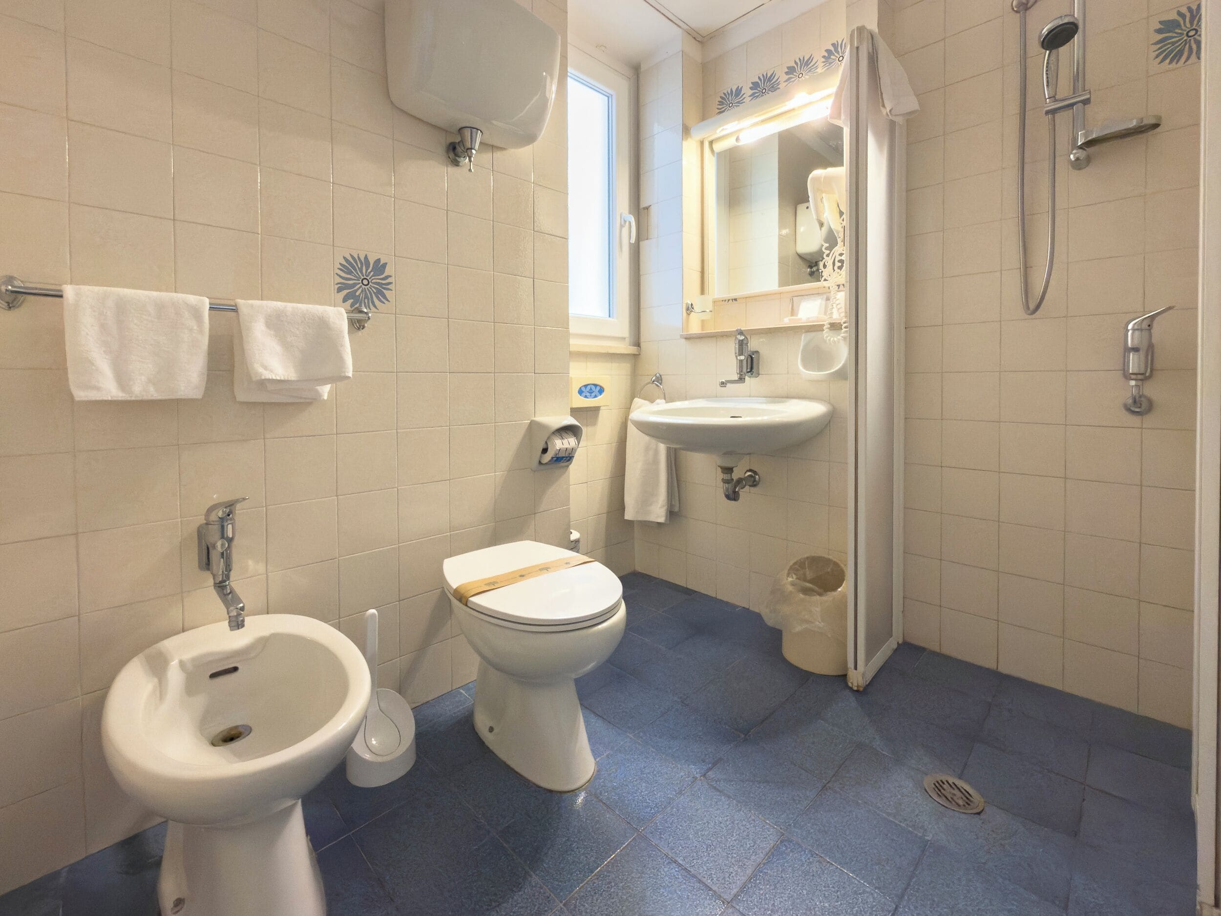 A bathroom with a bidet, toilet, sink, and a mirror.