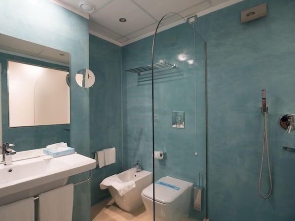 A bathroom with a sink, mirror, towel rack, shower, and toilet.