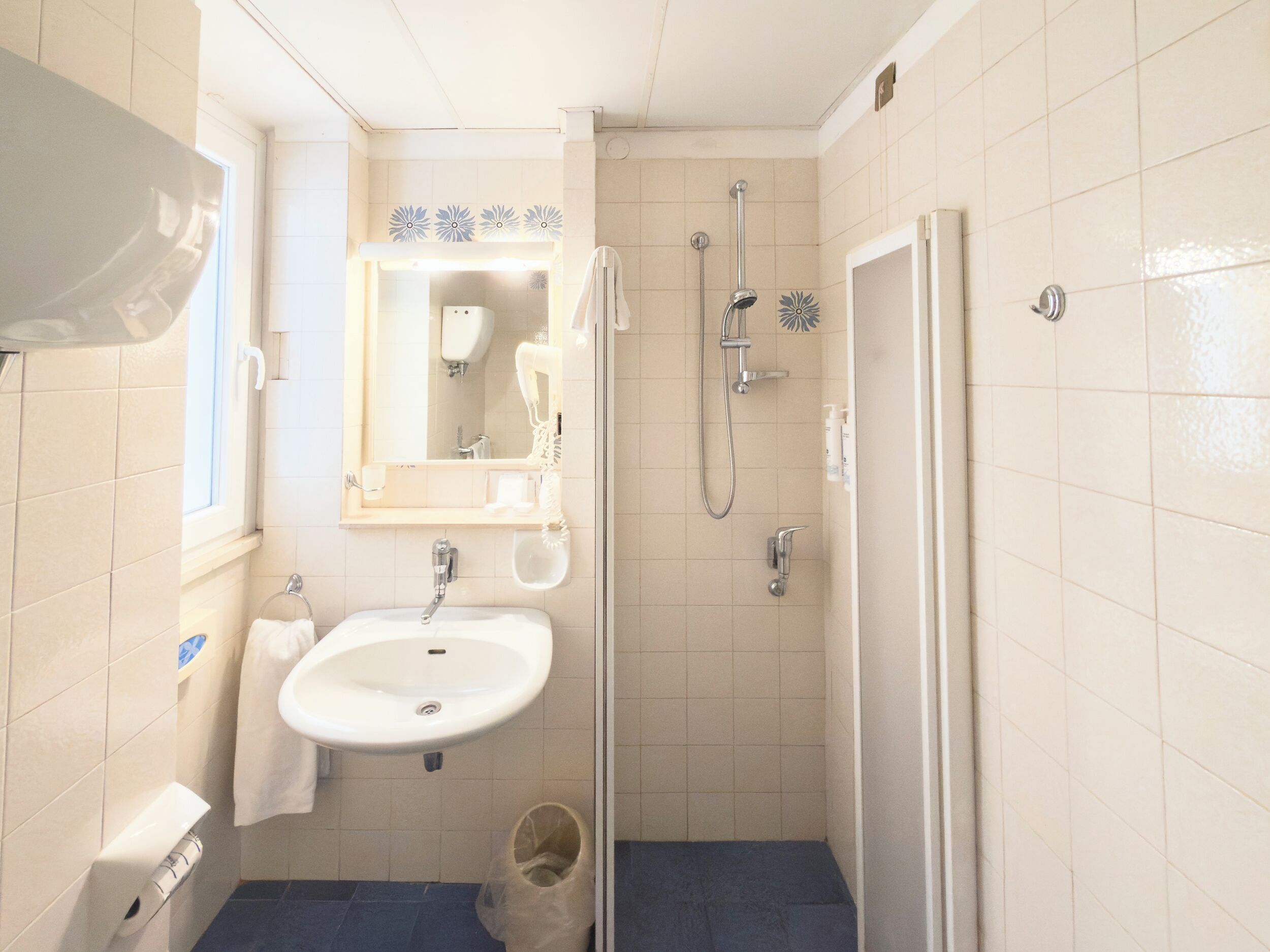 A bathroom with a white sink, a mirror, a shower, and a toilet.