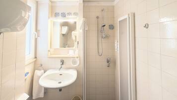 A bathroom with a white sink, a mirror, a shower, and a toilet.