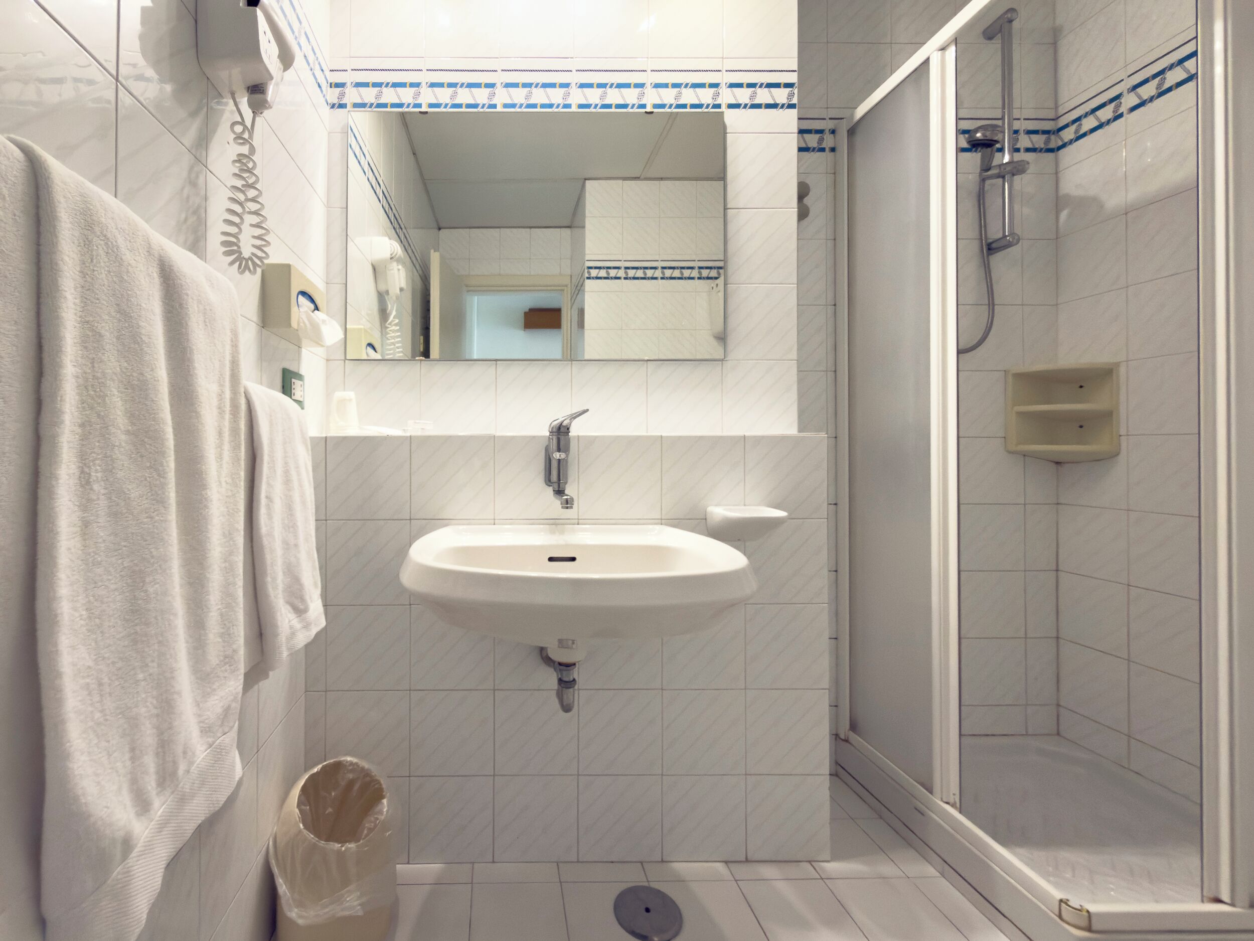 A bathroom with a sink, mirror, and shower.