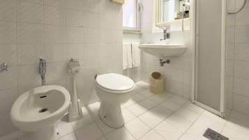 Un bagno con bidet, servizi igienici, lavandino e specchio.