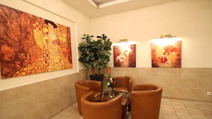 A lobby with a large abstract painting, a potted plant, and a seating area with a vase of flowers. - Hotel Atrium Charlottenburg (Berlin)