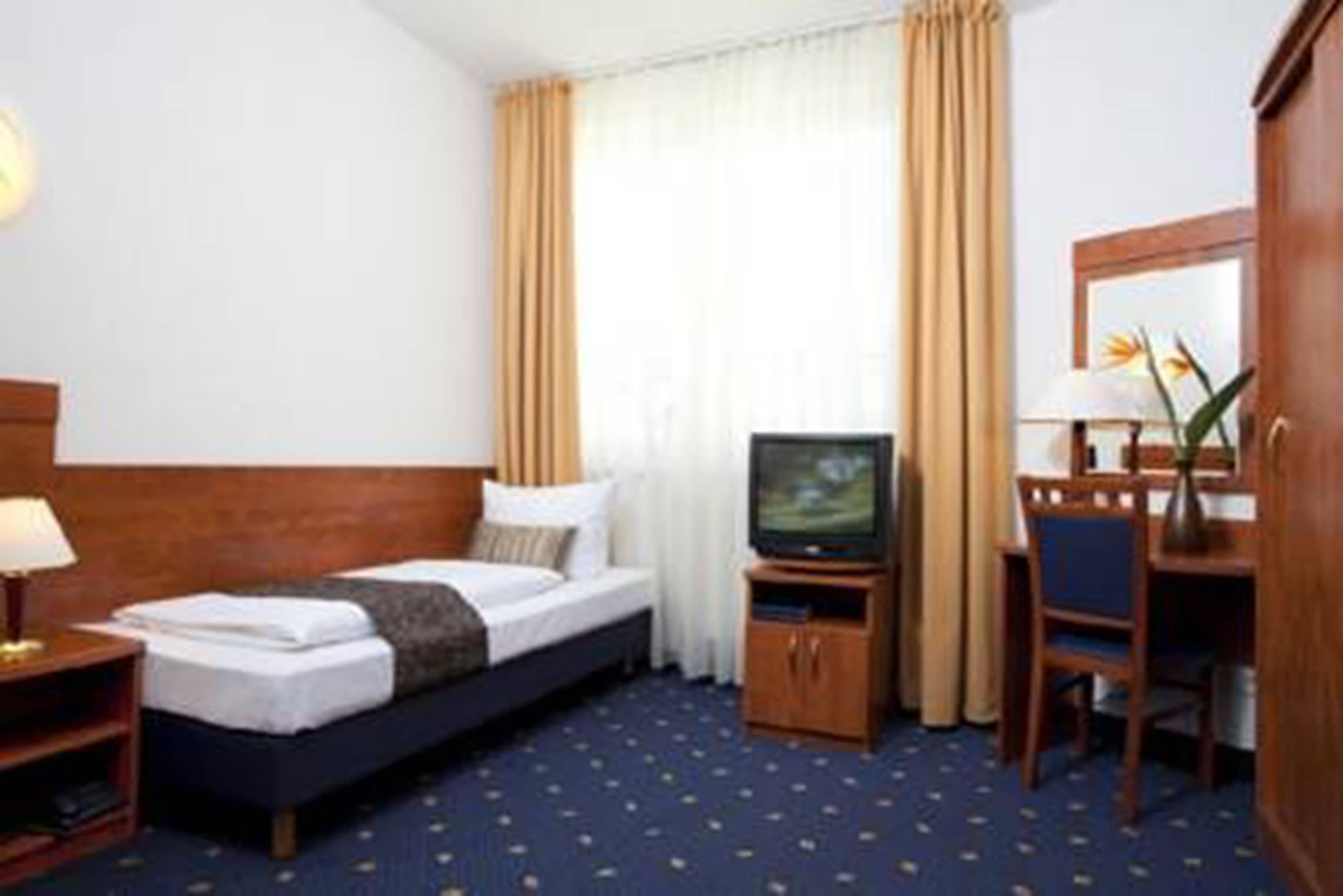 Une chambre d’hôtel équipée d’un lit, d’une télévision, d’un bureau et d’une chaise.