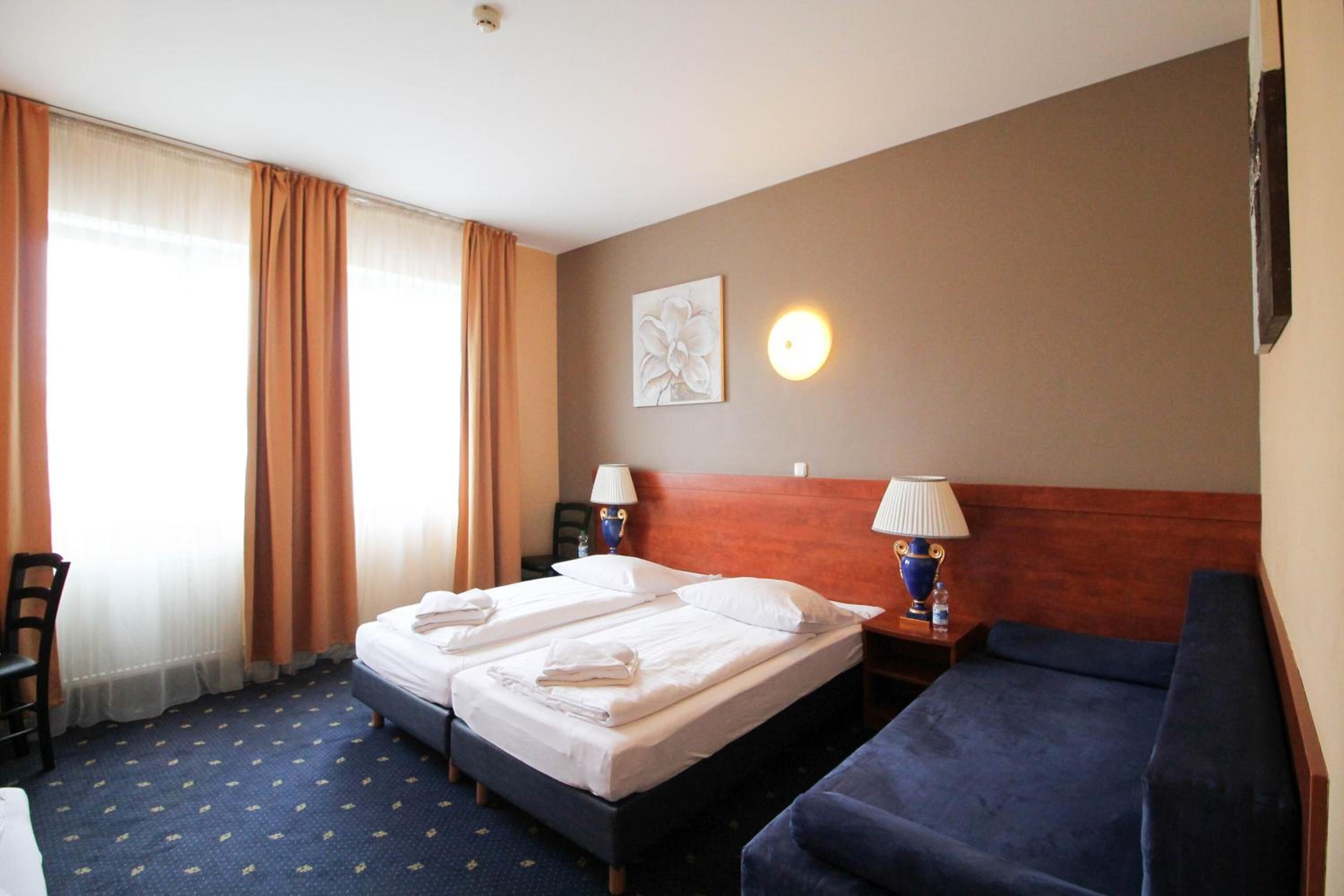A hotel room with two beds, a sofa, a desk, and a chair.