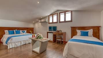 Habitación de hotel con dos camas, un escritorio y una kitchenette pequeña.