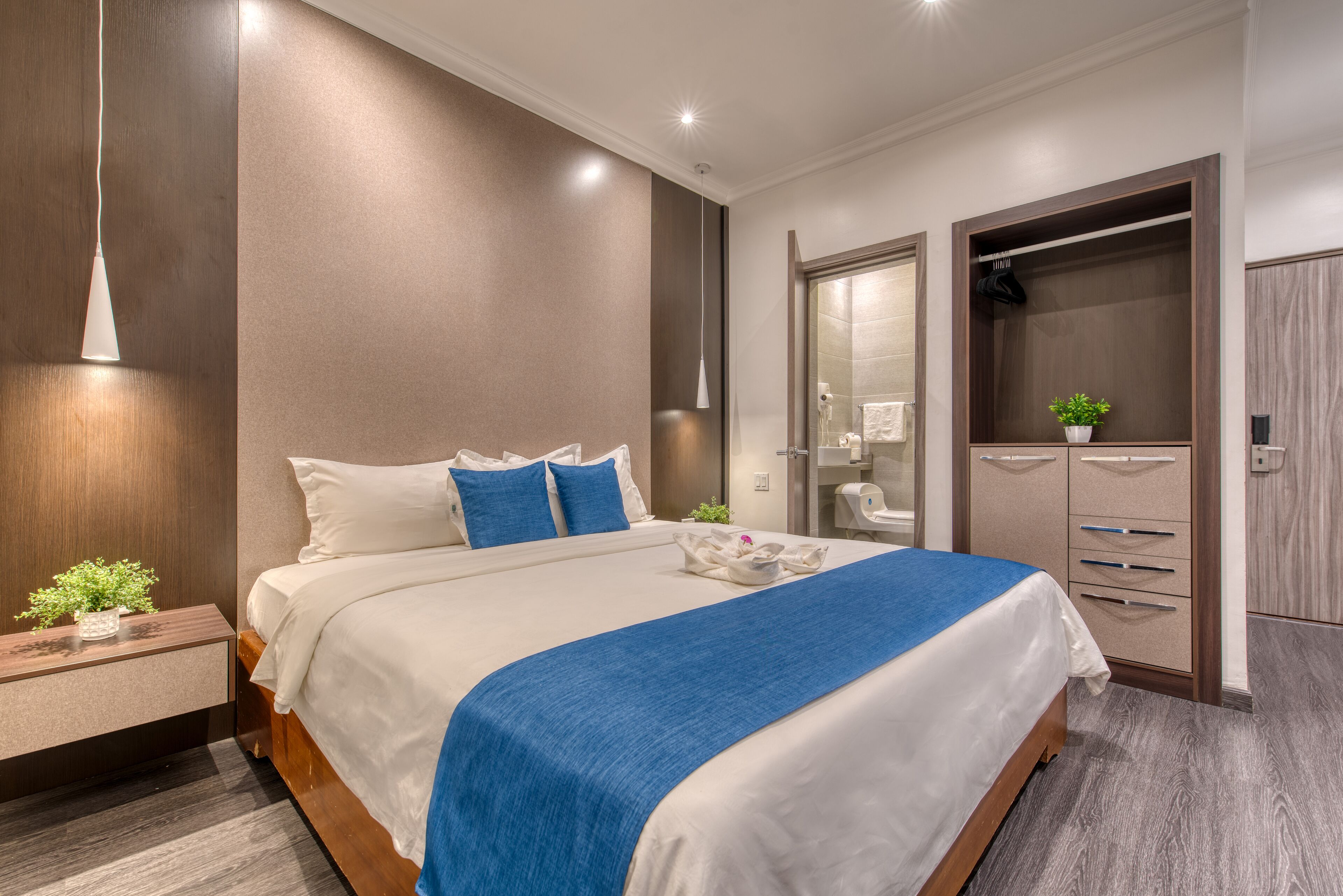 Una habitación de hotel moderna con una cama grande, mesitas de noche, un armario y un espejo.
