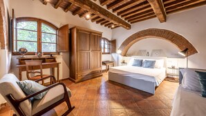 Ein Schlafzimmer mit einem großen Bett, Holzmöbeln und einem Steingewölbe.