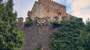 A historic stone castle with a fortified wall, a small arched entrance, and a metal staircase leading up to it. - Parador de Ciudad Rodrigo (Ciudad Rodrigo)