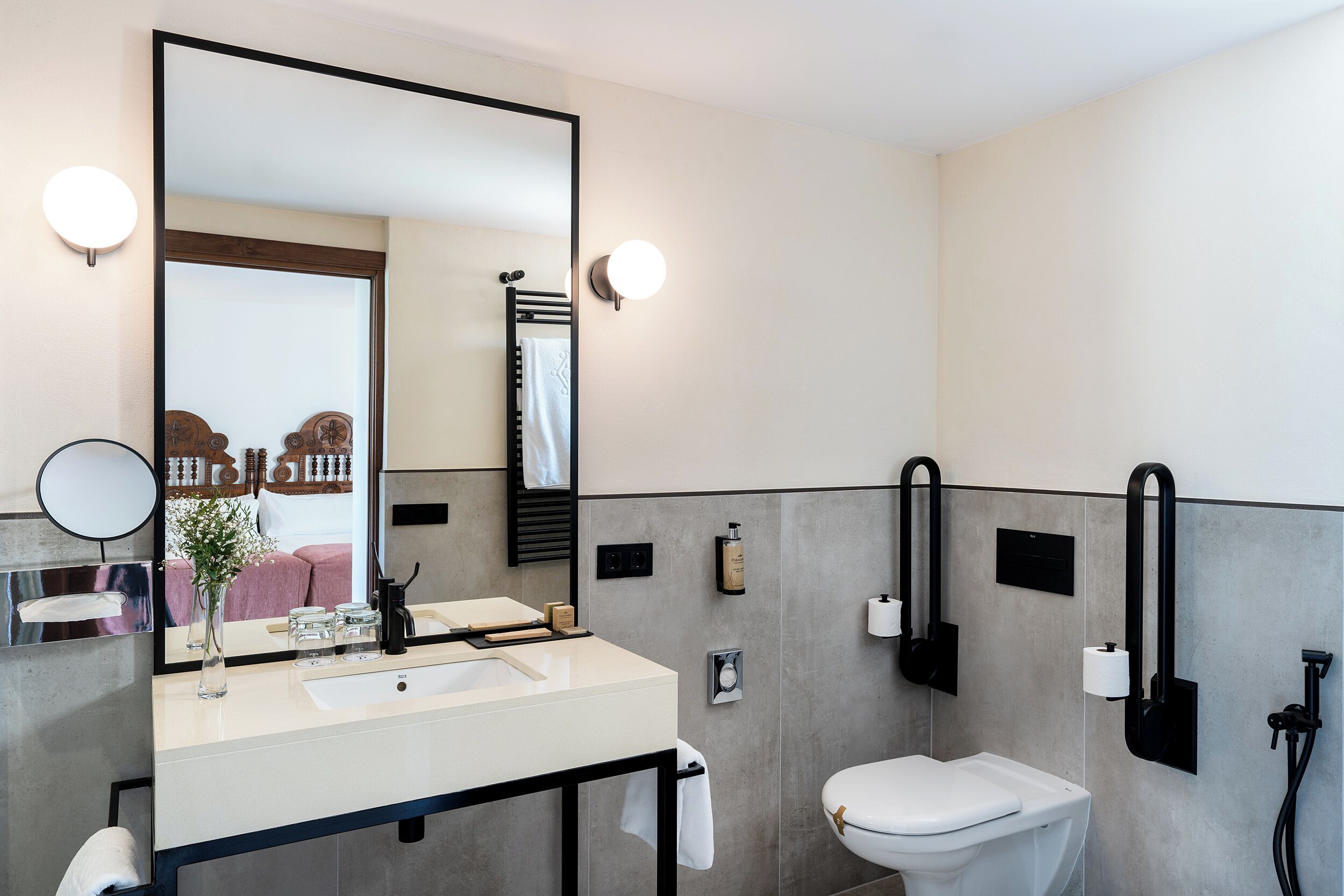 Un bagno moderno con uno specchio grande, un lavabo e un water. Sono presenti luci a parete e un porta asciugamani.