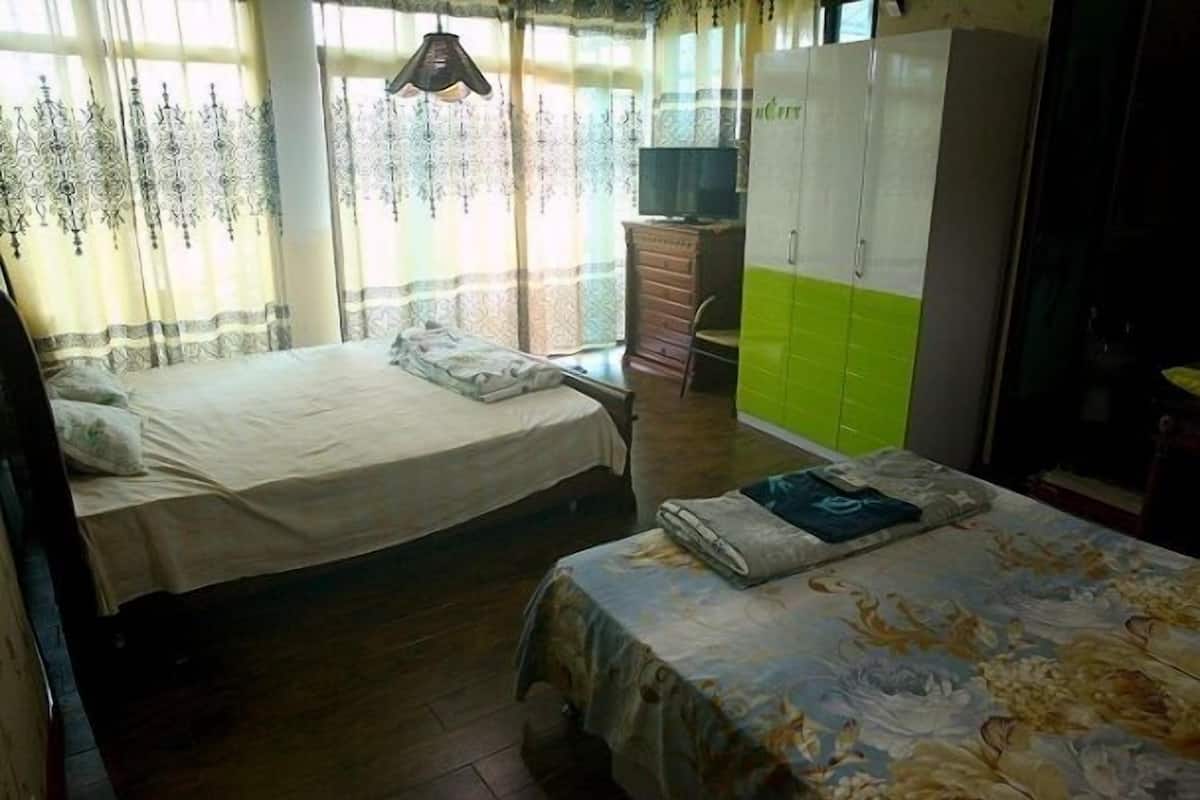 A bedroom with two beds, a wardrobe, and a desk.
