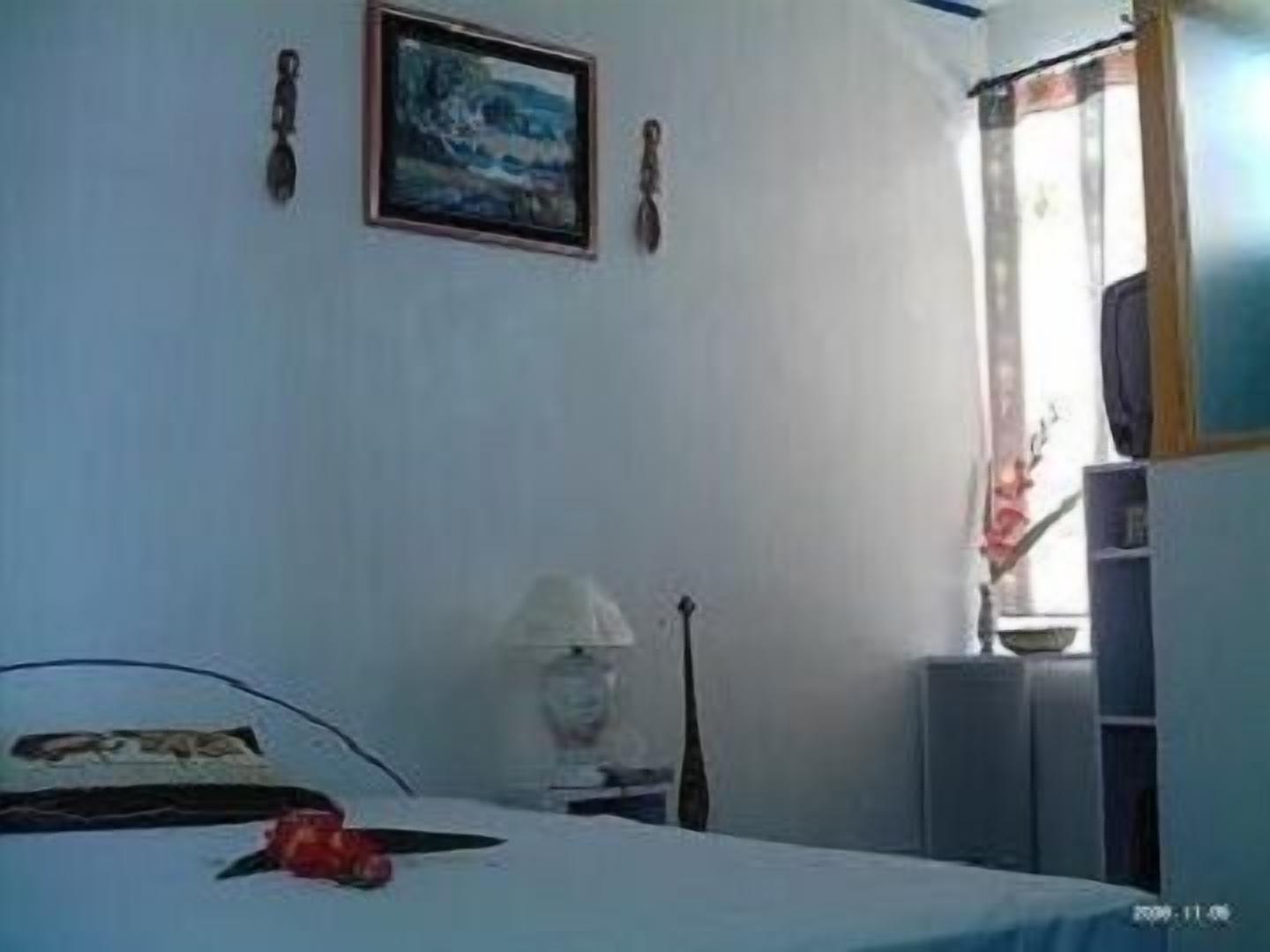 A bedroom with a bed, a lamp, a guitar, and a window with curtains.