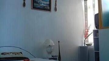 A bedroom with a bed, a lamp, a guitar, and a window with curtains.