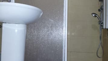 Un baño con un lavamanos blanco, una zona de ducha y un tapete colorido.