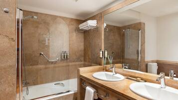 A modern bathroom with a glass-enclosed shower, two sinks, a large mirror, and marble walls.