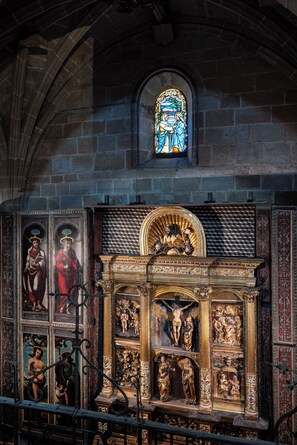 A church interior with a stained glass window, ornate religious paintings, and a detailed altar. - Parador de Calahorra (Calahorra)