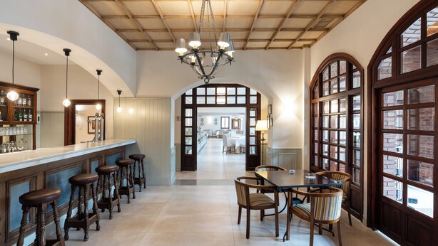 A spacious kitchen with a long counter, bar stools, and a dining area with a table and chairs. - Parador de Calahorra (Calahorra)