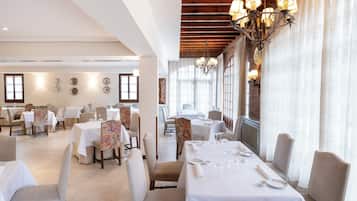 Zona pranzo con tavoli apparecchiati, sedie e un lampadario.