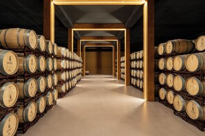 A long, narrow corridor lined with wooden barrels on both sides, leading to a central open space. - Parador de Calahorra (Calahorra)